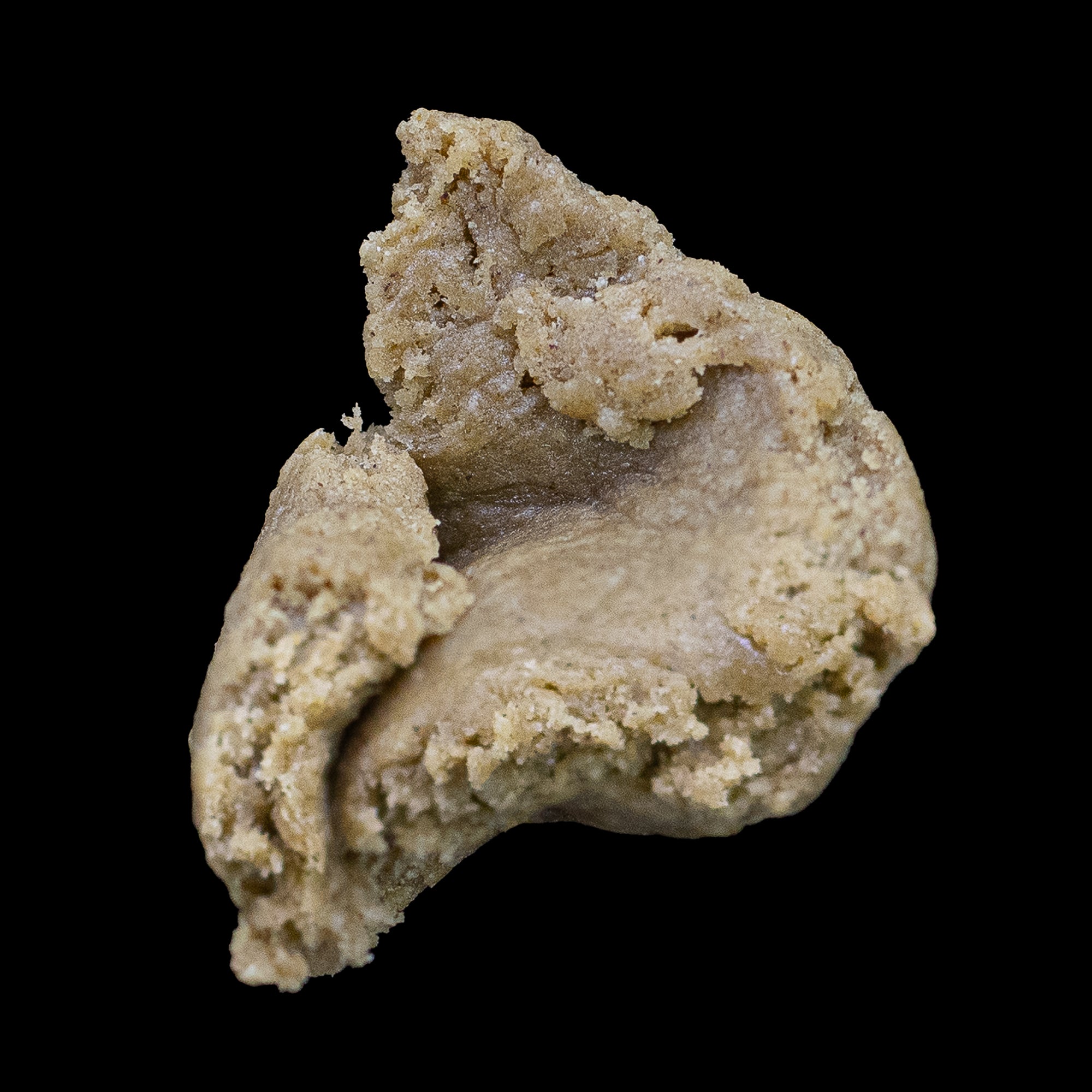 Et enkelt stykke Bubble Hash i lys brun farve med glat og smidig konsistens, formet naturligt og placeret mod sort baggrund for at fremhæve teksturen.