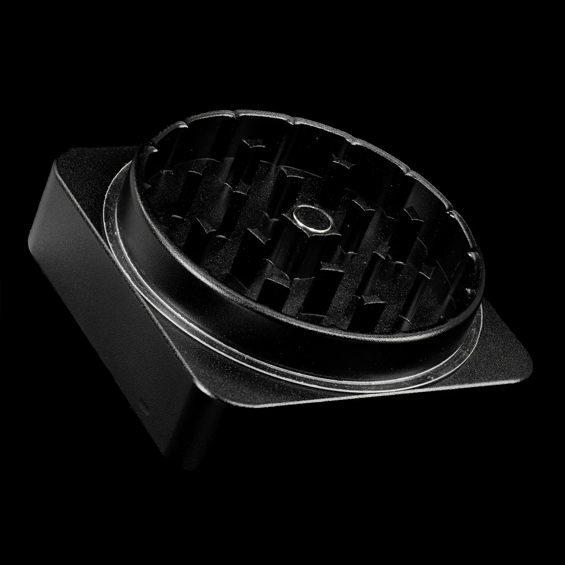 Nærbillede af den åbne Weedshop Grinder i sort metal med skarpe, diamantformede tænder og en magnetisk midte, designet til effektiv og ensartet maling af urter.